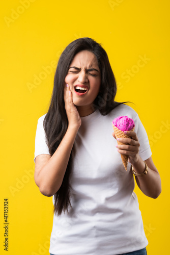 Photography Pretty Young Indian woman with sensitive teeth and eating cold ice cream on yell