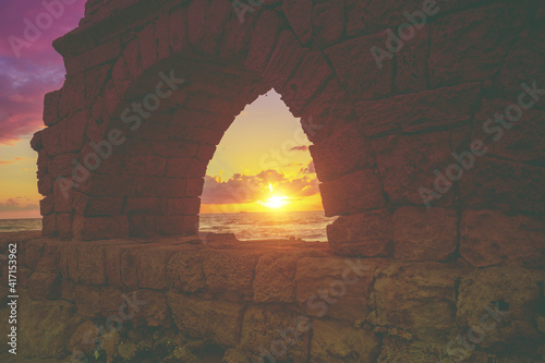 Remains of the ancient Roman aqueduct in ancient city Caesarea at sunset. Israel.