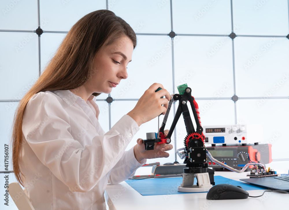 Woman student with industrial robot arm in laboratory Woman student with industrial robot arm in laboratory
