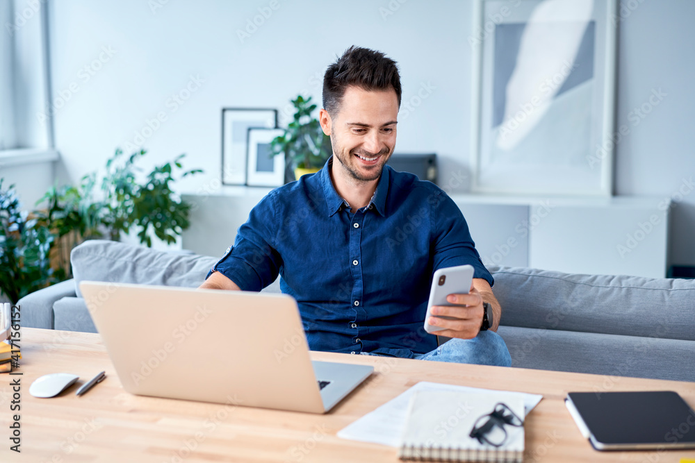 Young man working from home using mobile phone Young man working from home using mobile phone