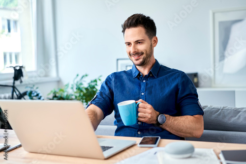 Happy man working at home, drinking coffee