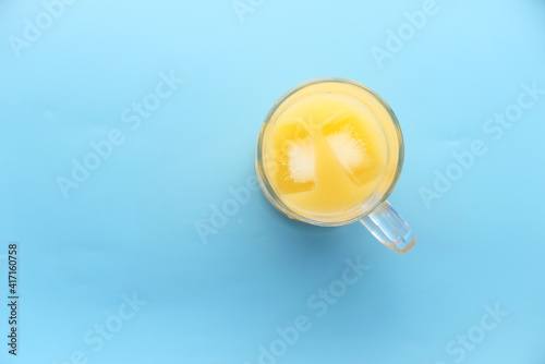 top view of a glass of orange juice with iece on blue background  photo