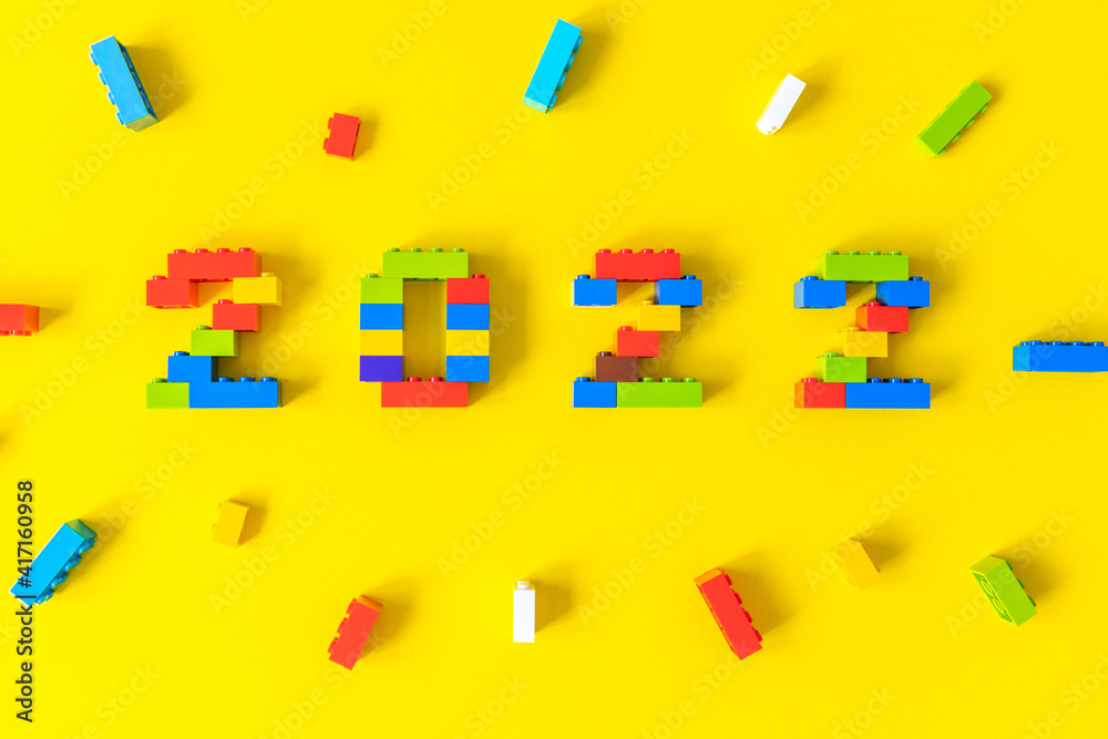 Obraz premium multicolored numbers 2022 from kids constructor set on isolated yellow background with place for text