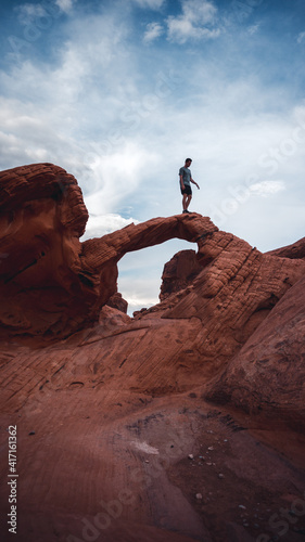 A person standing on a arches in the valley of fire state park, USA