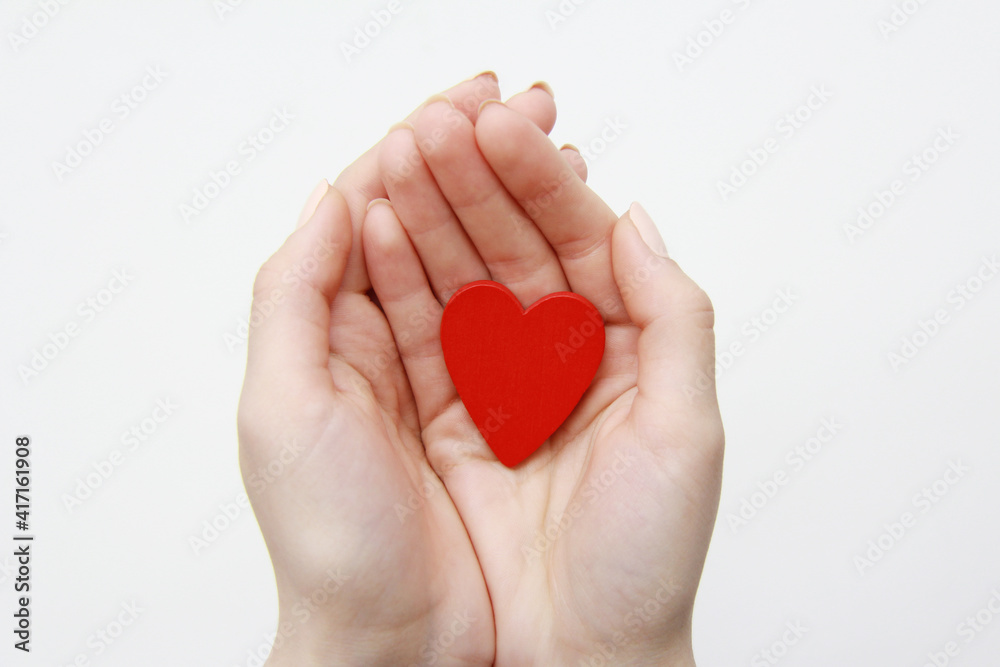 women's hands hold a red wooden heart on a white background. Health concept, love, organ donation, mindfulness, well-being, family, World Heart Day, World Health Day, National Organ Donor Day. women's hands hold a red wooden heart on a white background. Health concept, love, organ donation, mindfulness, well-being, family, World Heart Day, World Health Day, National Organ Donor Day.