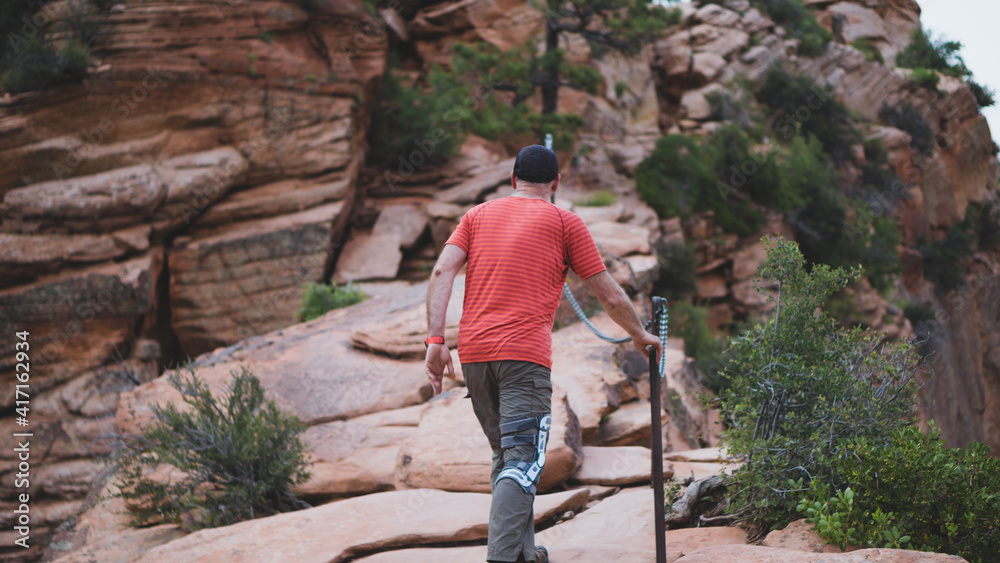 One man climbing up with wire ropes the angels landing in Zion National Park, Utah, USA