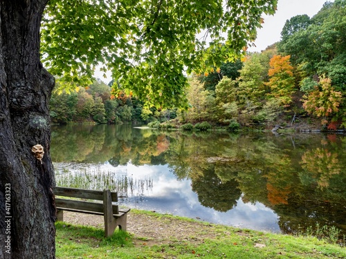 Tomlinson Run State Park in the fall in West Virginia with the fall colors and trees reflecting in the lake, the blue cloud filled sky in the background and a tranquil serene nature landscape scene. photo