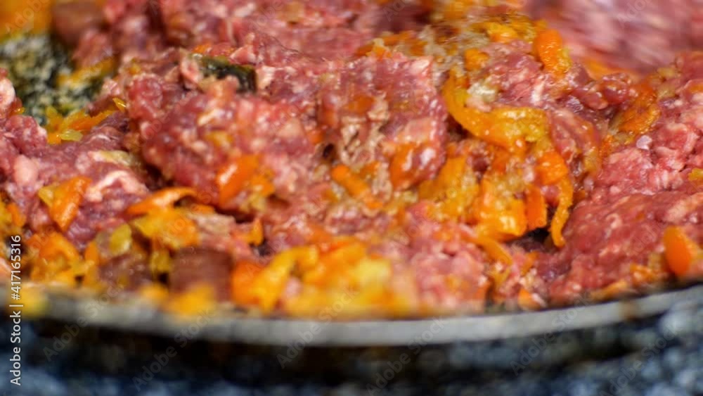 Raw minced meat putting in frying pan for cooking Bolognese sauce with tomatoes, olive oil, herbs, ham, carrot and mix thoroughly. Traditional italian food. Close-up. Raw minced meat putting in frying pan for cooking Bolognese sauce with tomatoes, olive oil, herbs, ham, carrot and mix thoroughly. Traditional italian food. Close-up.