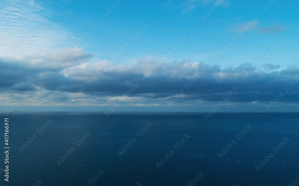 Dark blue sea surface under a cloudy sky.