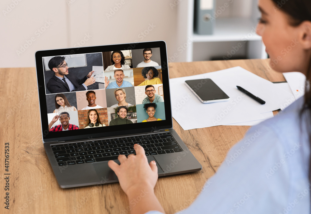 Back view of female employee having web conference on computer with colleagues Back view of female employee having web conference on computer with colleagues