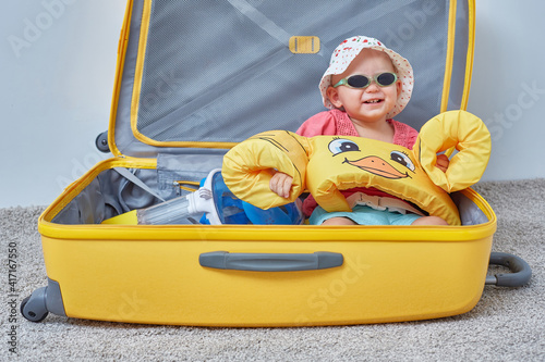 Child in a suitcase with things for a holiday at the sea or vacation travel