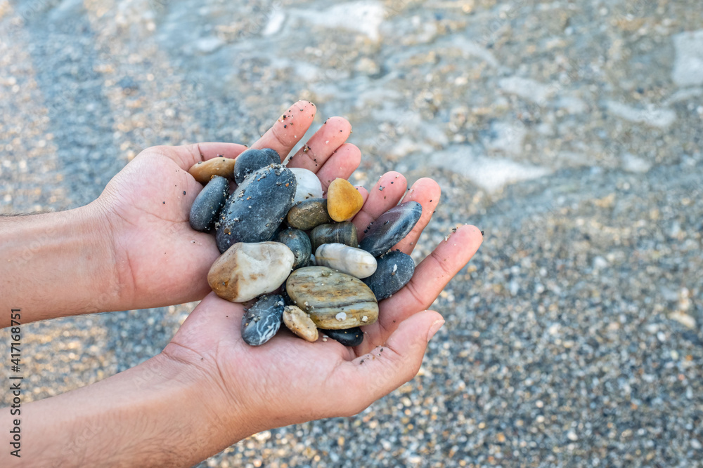 Stones in male's hands near the ocean Stones in male's hands near the ocean