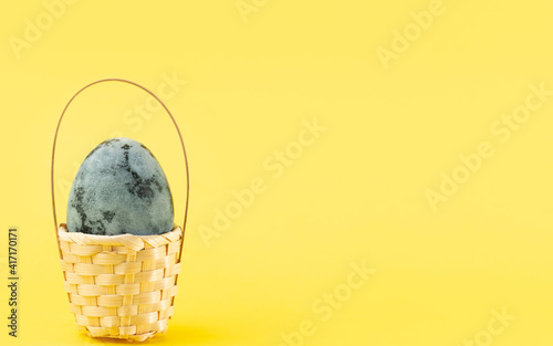 Easter egg in basket on a yellow background. Easter holiday concept. Copy space, close up
