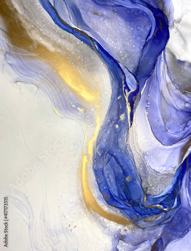 Abstract blue background with beautiful smudges and stains made with alcohol ink and gold pigment. Fragment of art with blue texture resembles watercolor or aquarelle painting.