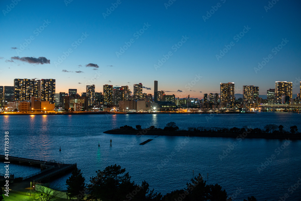 Tokyo Bay in the evening hours with a view of Tokyo skyline with tourists boards crossing the bay