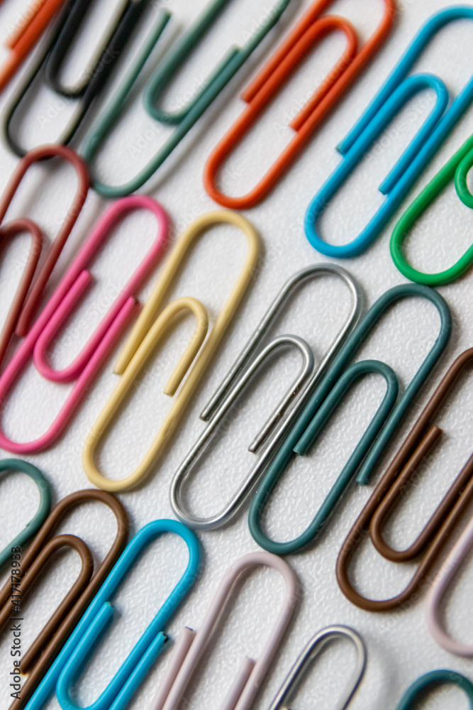 Many colorful paper clips on a home office desk for stationary design as colorful pattern to tidy desk, papers and paperwork to attach attachments to files and documents or collection of office supply Many colorful paper clips on a home office desk for stationary design as colorful pattern to tidy desk, papers and paperwork to attach attachments to files and documents or collection of office supply