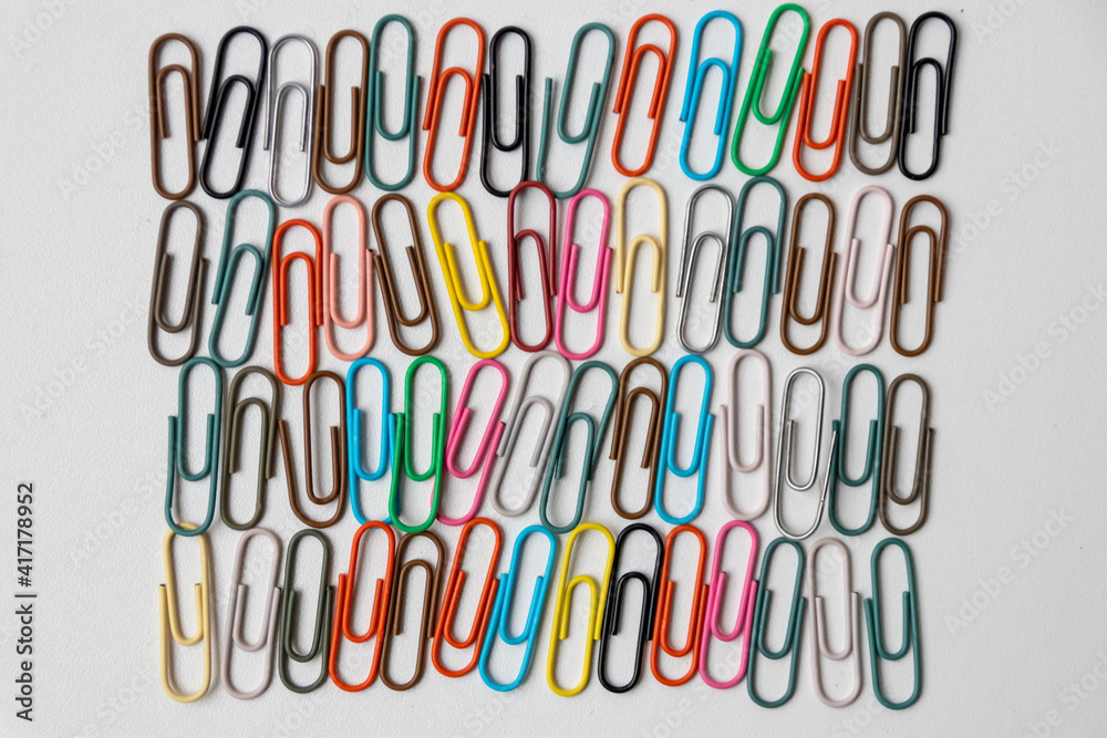Many colorful paper clips on a home office desk for stationary design as colorful pattern to tidy desk, papers and paperwork to attach attachments to files and documents or collection of office supply Many colorful paper clips on a home office desk for stationary design as colorful pattern to tidy desk, papers and paperwork to attach attachments to files and documents or collection of office supply