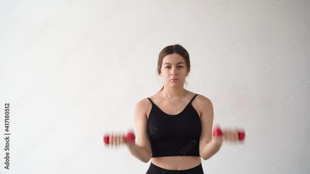 Beautiful sexy girl at home works out with dumbbells. Exercise for the muscles of the arm. white wall. Copy space. Beautiful sexy girl at home works out with dumbbells. Exercise for the muscles of the arm. white wall. Copy space.
