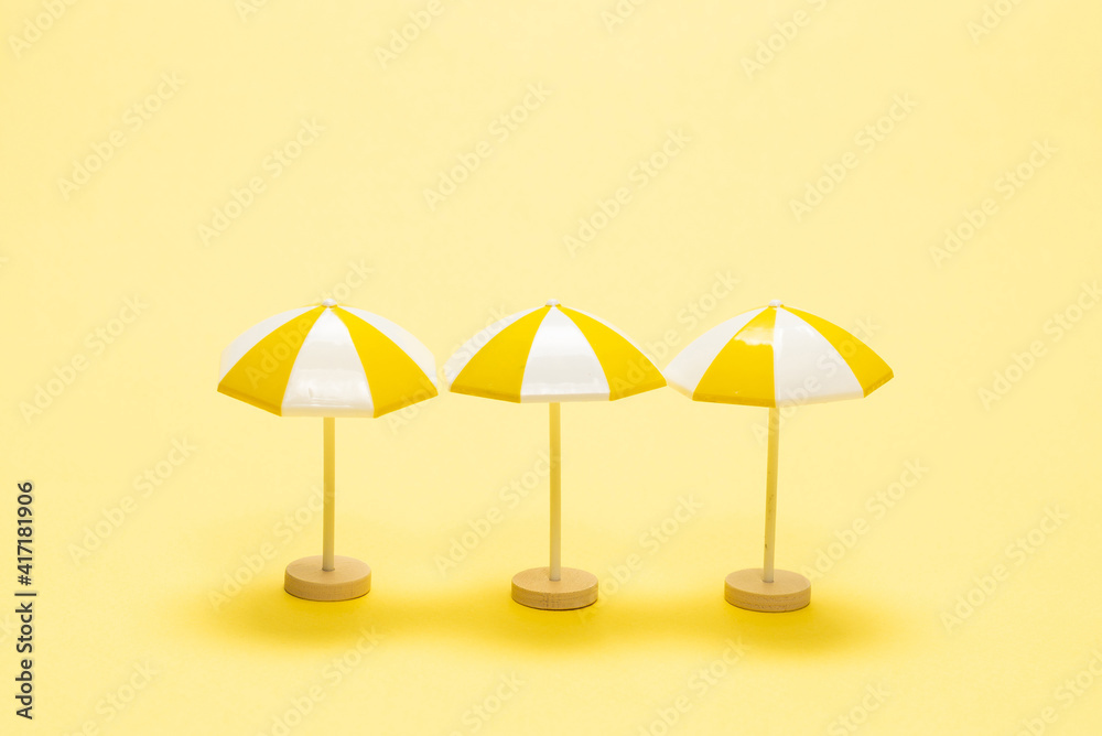 Sun lounger and yellow umbrella on a yellow background.