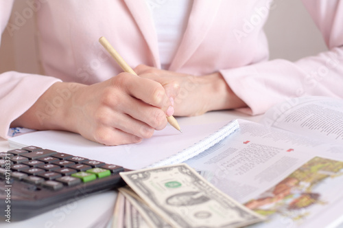 close up of woman hands with calculator counting and taking notes to notebook