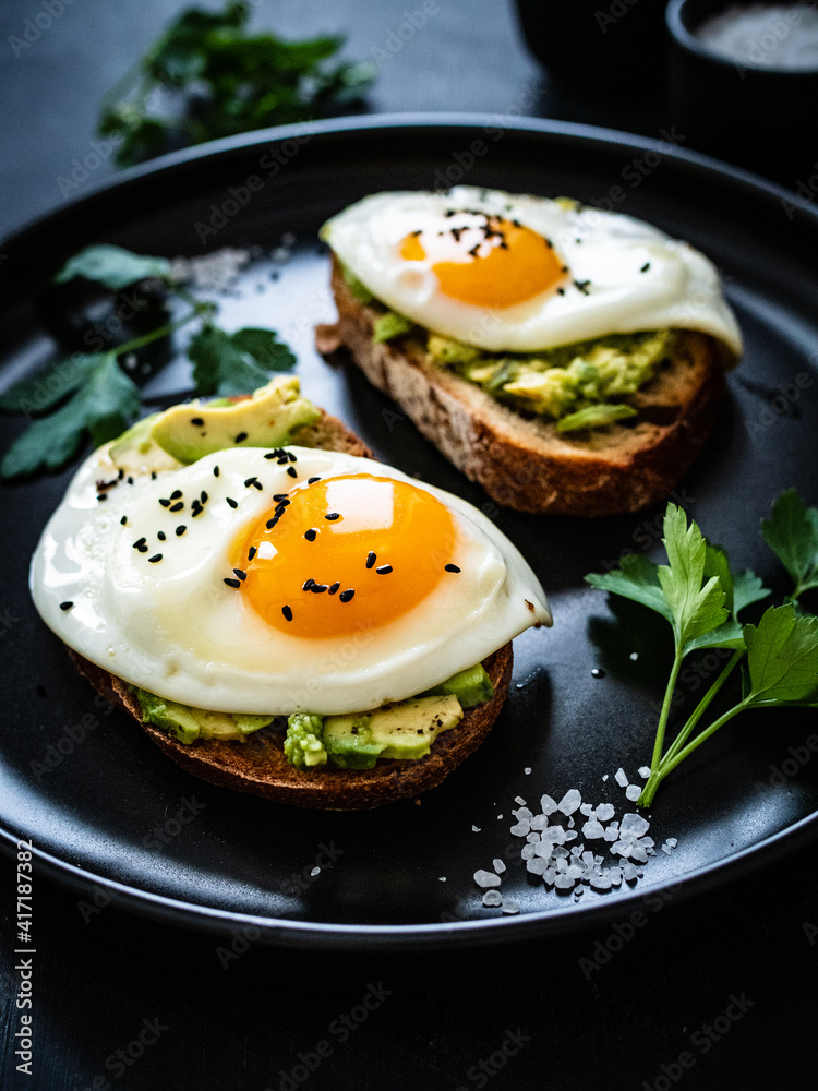 Continental breakfast - sunny side up eggs on toasted bread with avocado on black background
Continental breakfast - sunny side up eggs on toasted bread with avocado on black background