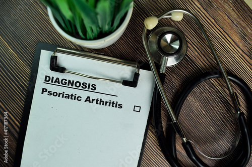 Diagnosis - Psoriatic Arthritis write on a paperwork isolated on Wooden Table. photo