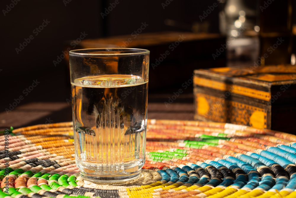 A glass of water on a Palestine home made rounded straw A glass of water on a Palestine home made rounded straw