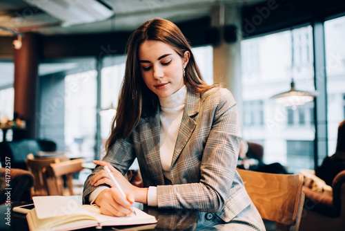 Focused female student taking notes while studying