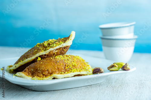 Ramadan sweets qatayef with white background and arabian coffee cups photo