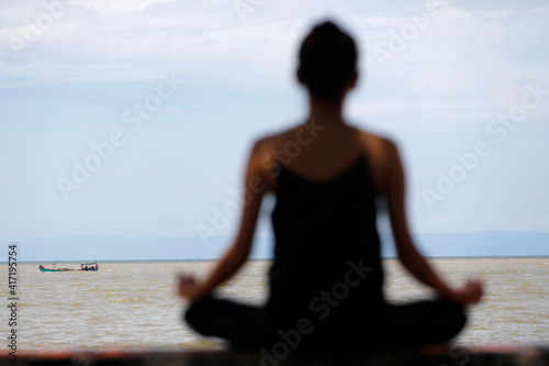 Silhouette of woman meditating in a lotus yoga position in front of the sea. Kep. Cambodia. 25.02.2017
