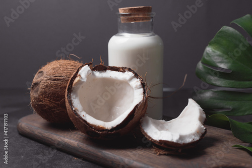 Canvas Print Glass bottle of milk or yogurt on dark wooden table with coconuts