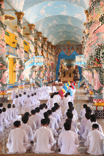 Cao Dai Holy See Temple. Praying devout men and women, ceremonial midday prayer. Thay Ninh. Vietnam.
