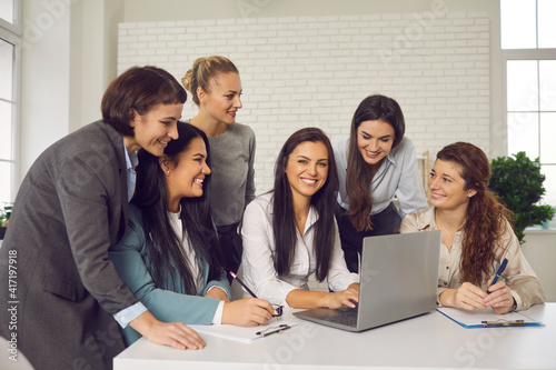 Good friends and business partners working on professional e-commerce project together. Cheerful positive women meeting in office, using laptop and discussing new creative ideas for their online store