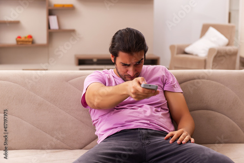 Young man watching tv at home during pandemic