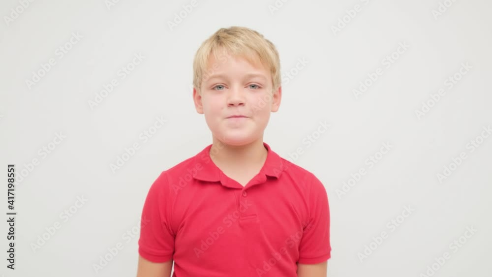 The boy is having fun and dancing on a white background in the studio in a red T-shirt. The boy is having fun and dancing on a white background in the studio in a red T-shirt.