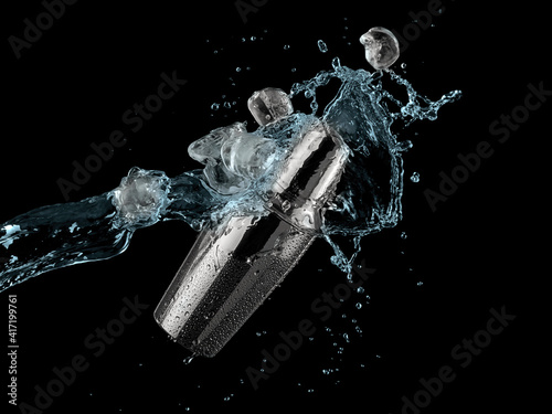 Cold water with ice cubes splash over a metal cocktail shaker on black background