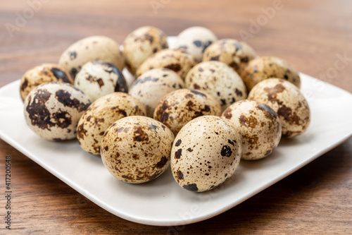Fresh small spotted partridge eggs on white board
