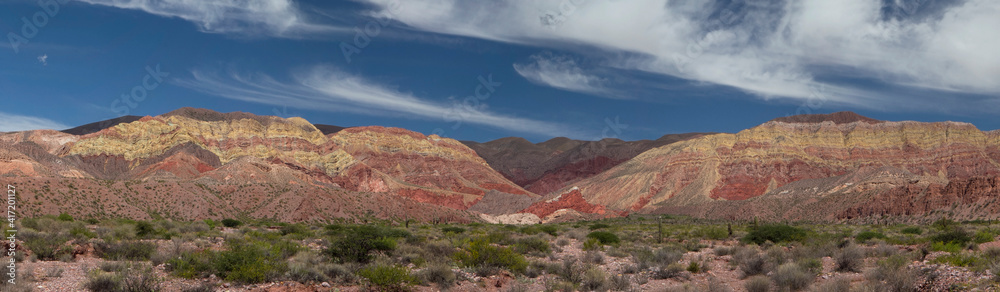 Desert background. Panorama view of the arid desert and colorful mountains under a blue sky. Desert background. Panorama view of the arid desert and colorful mountains under a blue sky.