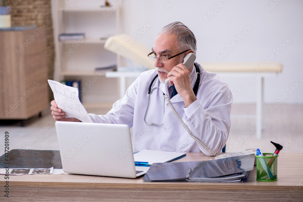 Old male doctor cardiologist working in the clinic Old male doctor cardiologist working in the clinic