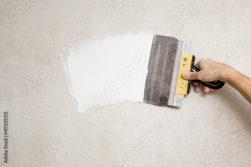 Konstfotografi Young adult man hand using spatula and plastering wall with white fresh finishing putty