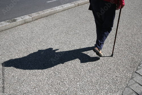 Elderly woman walking outside with a walking stick.  France. 14.12.2016