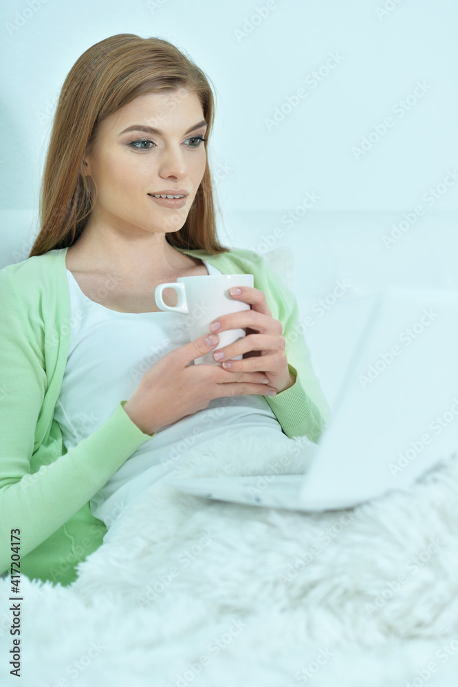 Young woman using laptop in bed at home Young woman using laptop in bed at home