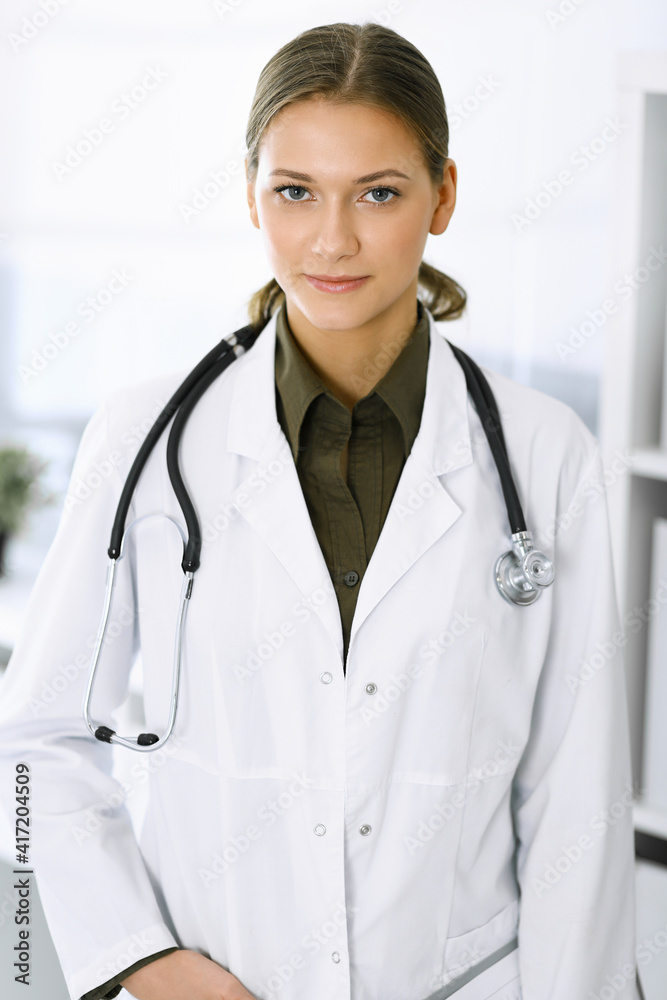 Woman-doctor standing and looking at camera. Perfect medical service in clinic. Medicine and healthcare Woman-doctor standing and looking at camera. Perfect medical service in clinic. Medicine and healthcare