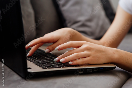 close-up of a girl's hands typing on a laptop keyboard