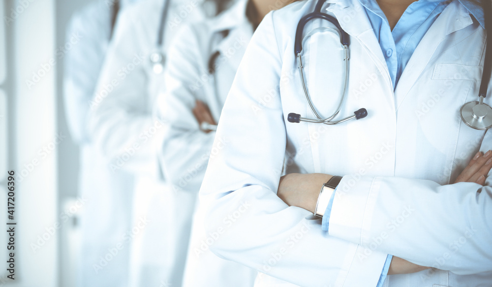 Group of modern doctors standing as a team with arms crossed in hospital office. Medical help, insurance in health care, best desease treatment and medicine concept Group of modern doctors standing as a team with arms crossed in hospital office. Medical help, insurance in health care, best desease treatment and medicine concept