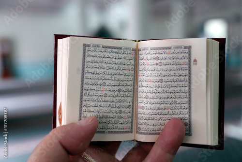 The Green Mosque. Muslim man reading an Arabic Holy Quran (Koran). Singapore.. 25.02.2017