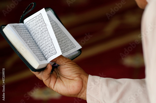Masjid Ar-Rohmah mosque. Muslim man reading an Arabic Holy Quran (Koran). Chau Doc. Vietnam. 21.09.2018