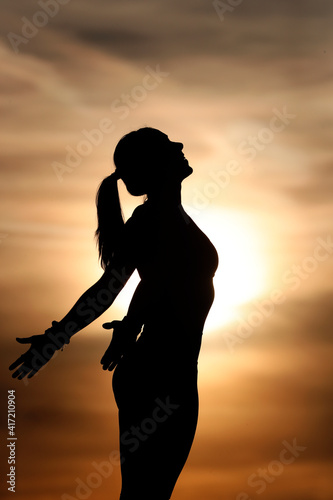Photos Silhouette of a woman practising yoga against the light of the evening sun