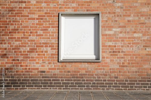 Brick wall with window, white frame with space for text, stonewall with bricks, white window and street