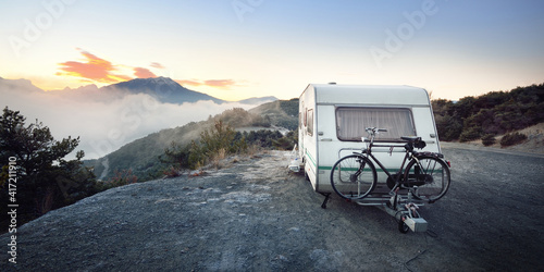 Fotobehang Caravan trailer with a bicycle near mountain lake Lac de serre-poncon in French Alps at sunrise